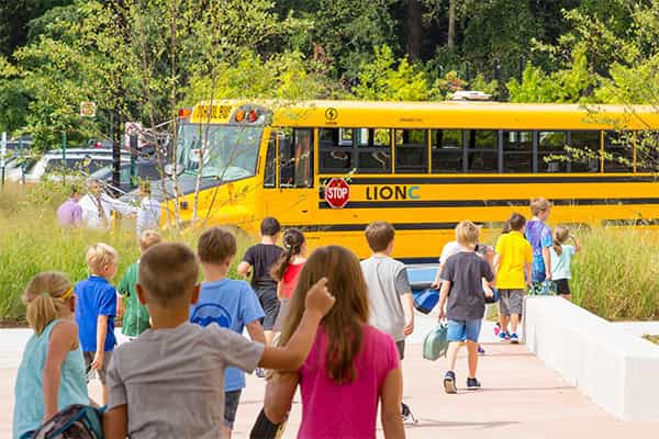Enfants qui courent pour monter à bord d'un autobus scolaire électrique